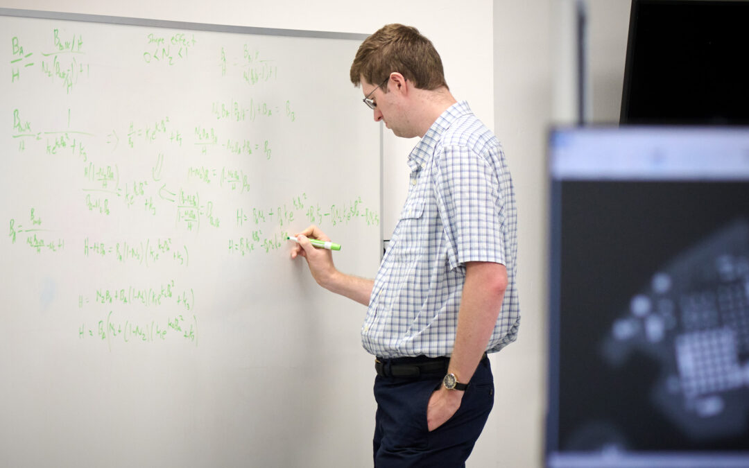 Man doing equations on a board at Intricon